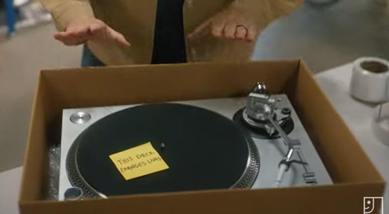 illustration of person donating a box with a record player with a sticky note that says "This Deck Changes Lives"
